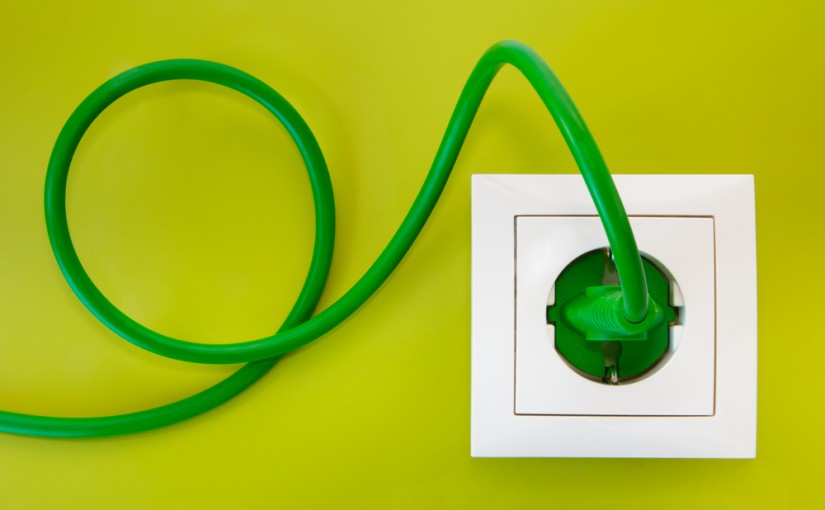 Green power plug into white power outlet against a olive green background